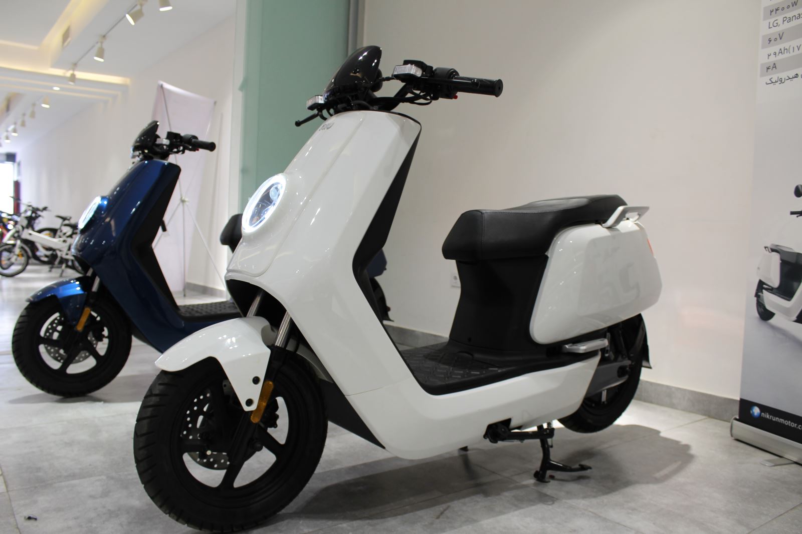 موتورسیکلت برقی سفید رنگ پارک شده در نمایشگاه سازمان برنامه و بودجه