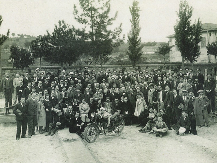 تعدادی زیاد افراد در کنار هم در کنار نمونه ی اولیه ی موتورسیکلت