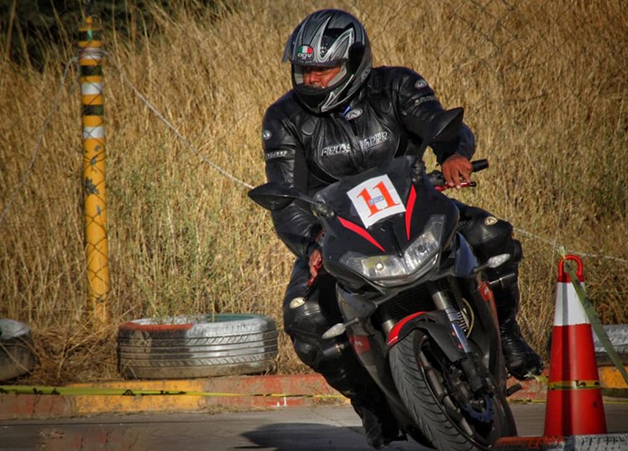 عکس پیست مسابقه یک موتورسوار در حال سواری با موتورسیکلت شماره 11است، لباسش کامل سیاه رنگه،یک کلاه ایمنی سیاه رنگم داره،